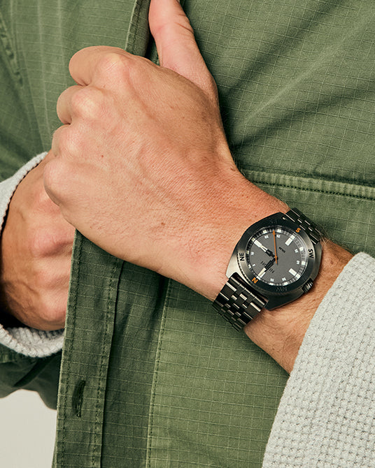 Man wearing the Nixon Oco 44 analog compass watch while wearing a green jacket