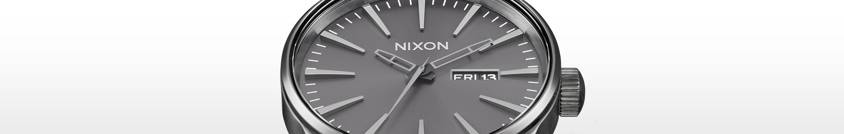 Close-up of a Nixon Sentry watch with a gunmetal grey dial, silver hands, and markers, displaying "FRI 13".