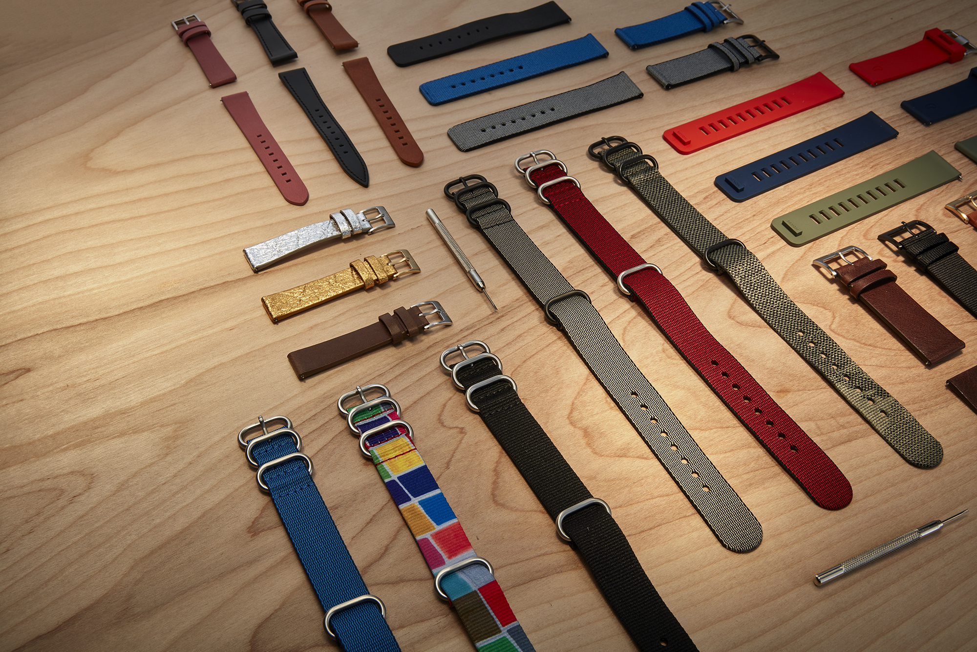 A collection of Nixon watch bands sits on a wooden table.