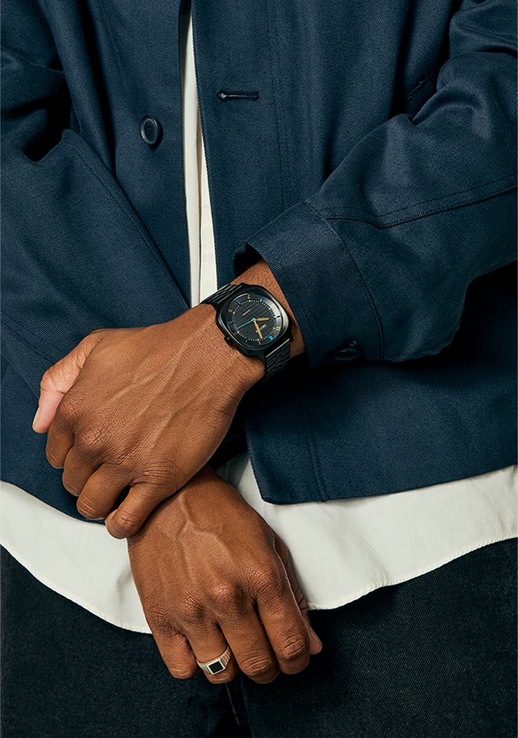 Man with arms crossed wears the Nixon Fremont 40 analog watch