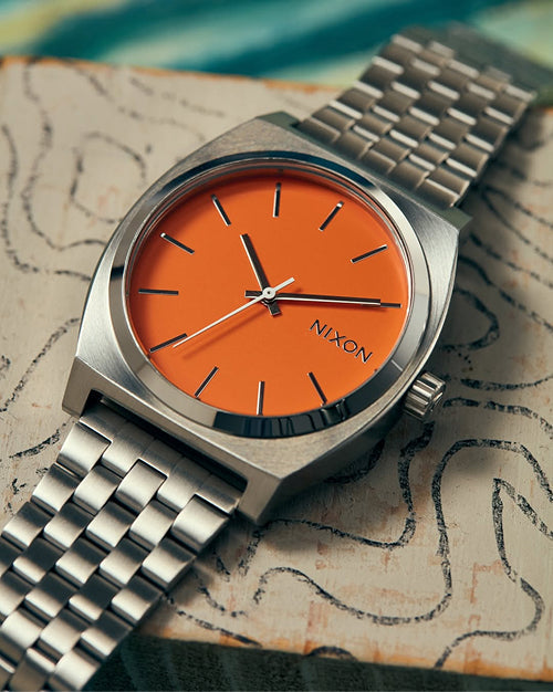 A Nixon Time Teller analog watch rests on a unique background
