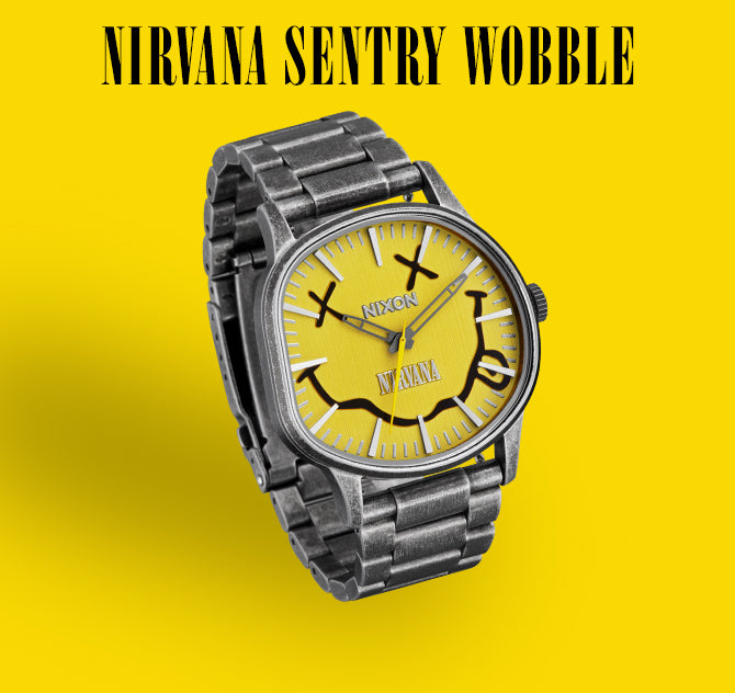 A Nixon "Nirvana Sentry Wobble" watch with a yellow face featuring the iconic Nirvana smiley face logo, set against a bright yellow background.