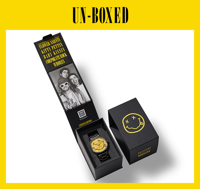 A black Nixon Nirvana limited edition watch with a yellow smiley face dial, presented in an open black box featuring band photos and song lyrics, alongside a closed box with the iconic Nirvana smiley logo.